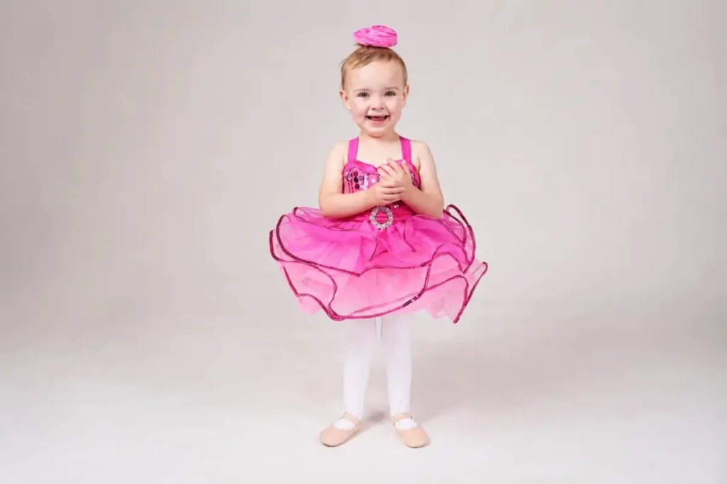 Smiling toddler girl in pink ballet tutu and ballet slippers