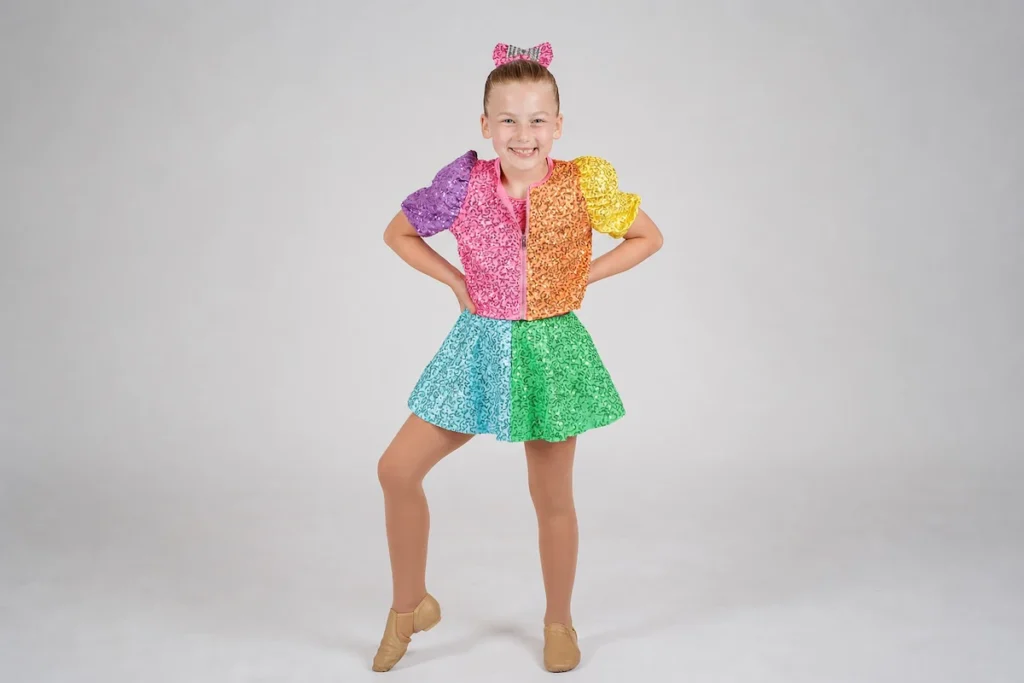 Young girl dancer in colorful rainbow sequin costume posing