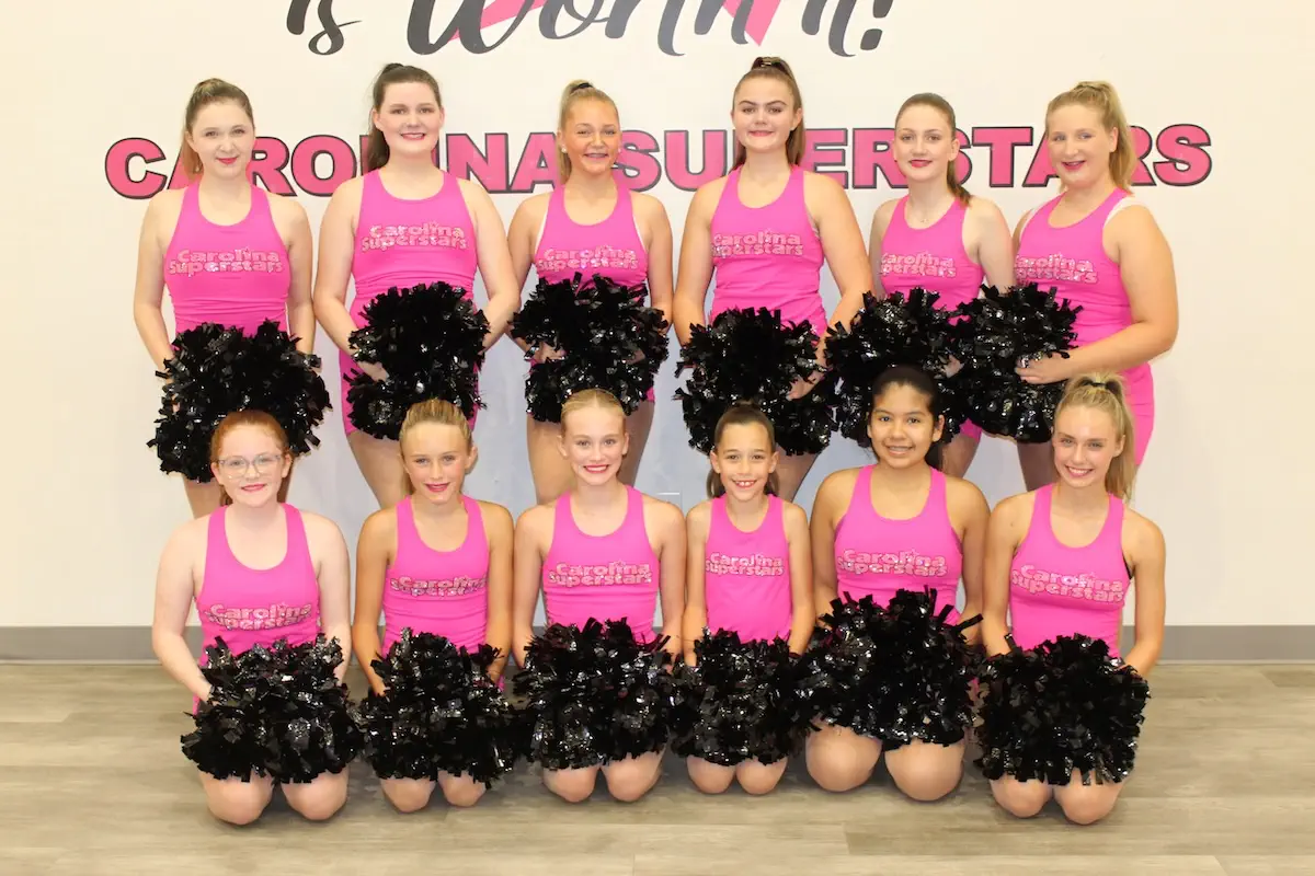 Carolina Superstars dance team in pink uniforms with black pom-poms