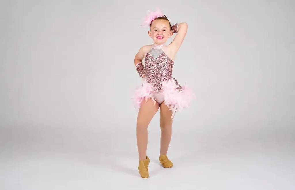 Young girl in pink sequin dance costume posing and smiling