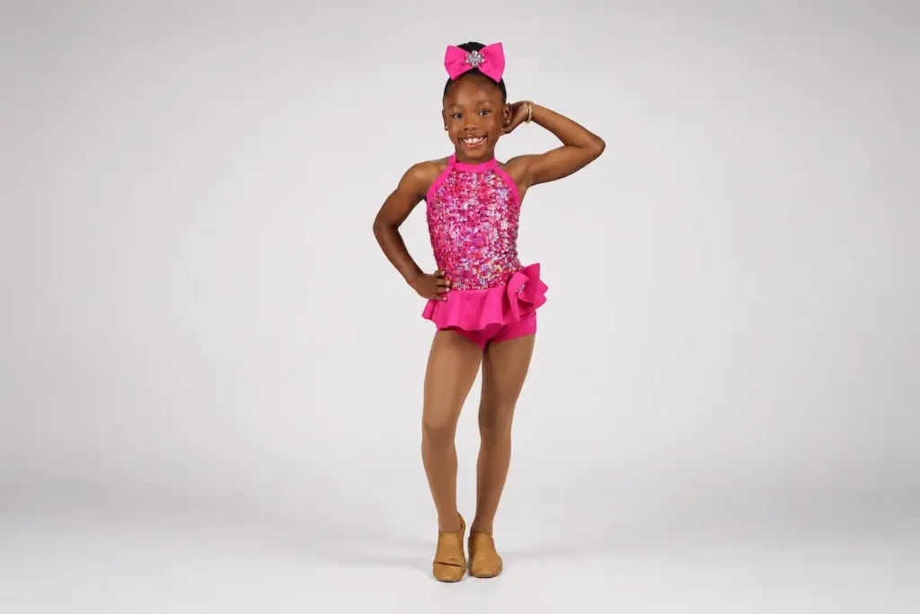 Young girl in pink sequin dance costume posing