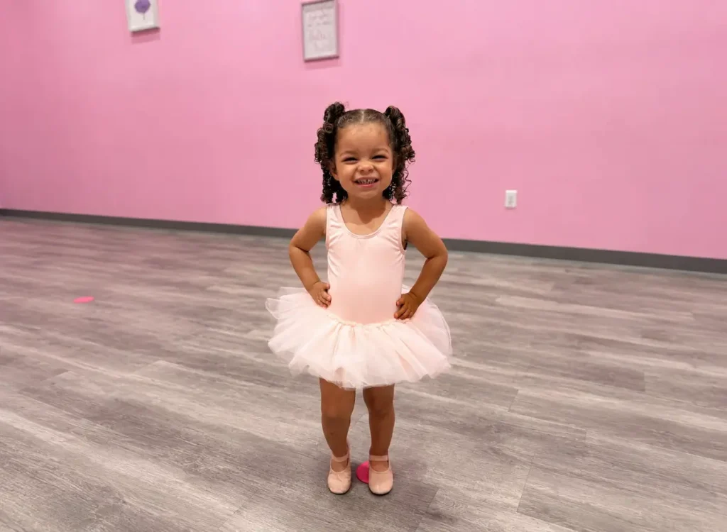 Smiling toddler girl in pink ballet tutu at dance studio