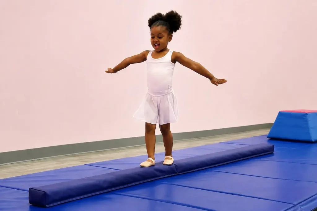 Young girl in white leotard balancing on gymnastics beam