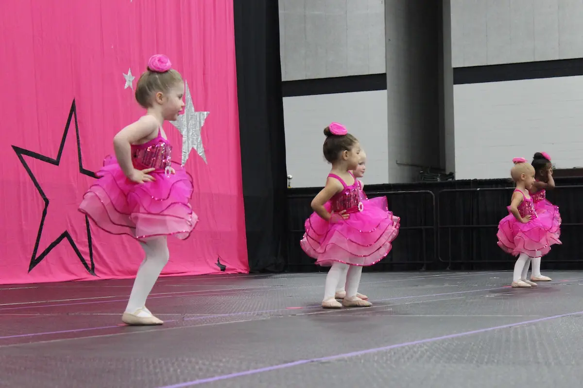 Young girls in pink tutus performing ballet on stage