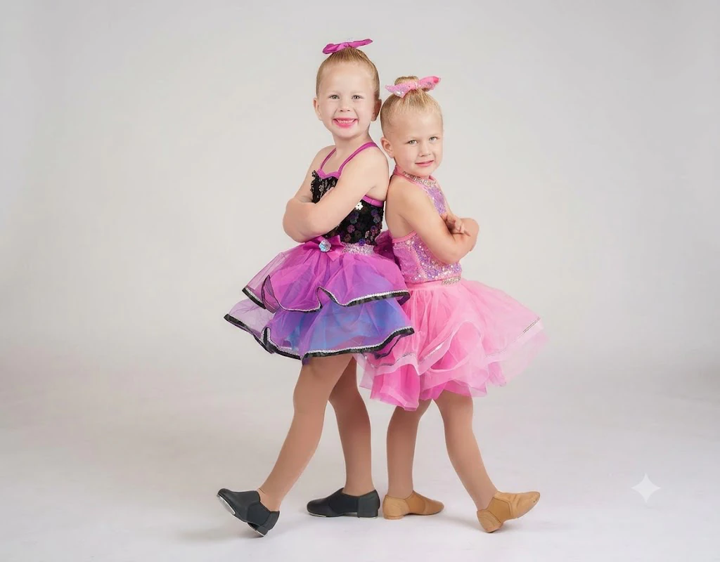 Two young girls in pink dance costumes posing back-to-back